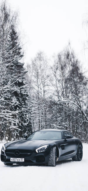 冬季雪地森林中停放的黑色跑車。