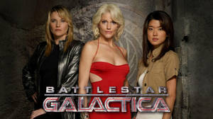 三位身穿科幻服裝的女性在帶有 Battlestar Galactica 標誌的石牆前擺姿勢。 — 電影 壁紙