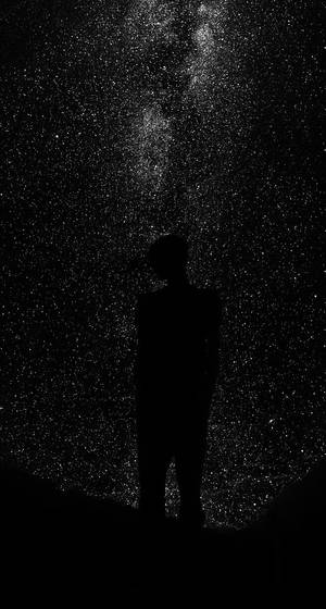 一個人在星空下仰望銀河的剪影。