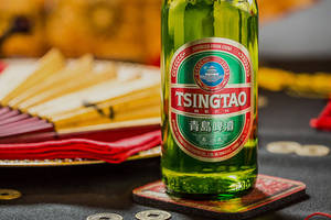 青島啤酒瓶與中國扇子和硬幣放在桌上。