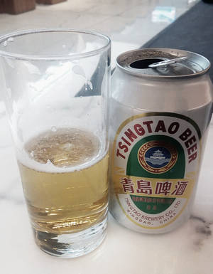 冰凍青島啤酒罐和玻璃杯放在大理石檯面上。