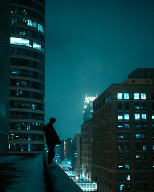 一個人站在屋頂上俯瞰夜晚城市的剪影。