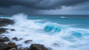 藍綠色的海洋波浪在暴風雨的天空下衝擊著深色岩石。