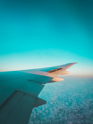 日出時飛機機翼在蓬鬆的雲層上方翱翔