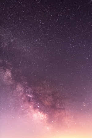 銀河系在繁星點點的夜空中散發出紫色和粉紅色的色調。