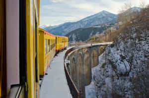 黃色火車穿越山谷中的雪石橋