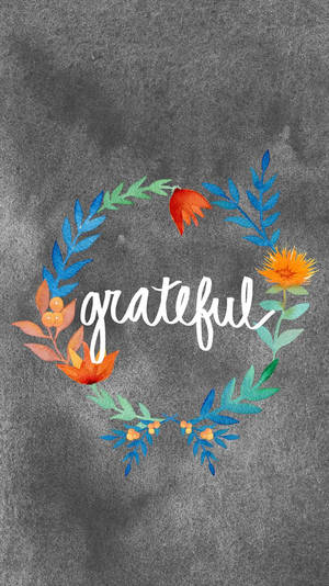 一個色彩繽紛的水彩花環，中央放置「grateful」這個詞，背景為有紋理的灰色。