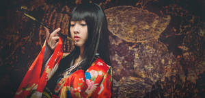 身穿紅色花卉和服的女子，在深色質感背景前手持煙斗。 — 日本 壁紙