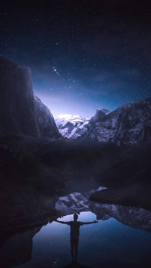 人在湖中張開雙臂，星空下，有雪山倒影