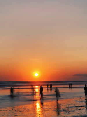 人們在濕沙灘上行走，橙色夕陽映照海洋