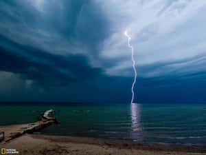暴風雨中閃電擊中海洋，前景有碼頭。