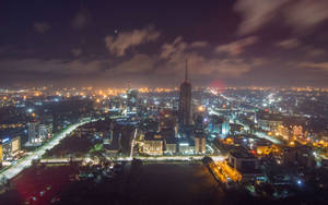 星空下，高樓大廈和發光的街道照亮城市的夜間航拍圖。