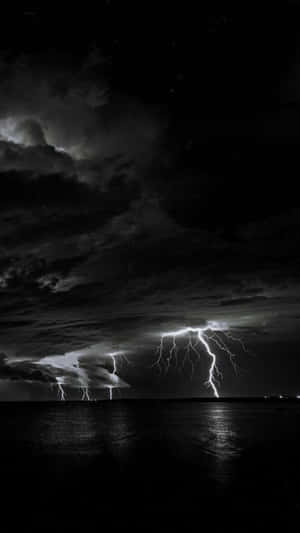 夜晚暴風雲下，黑暗水面上閃電擊中。