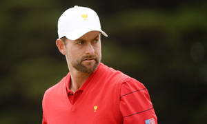 高爾夫球手穿著紅色襯衫和帶有金色獎盃標誌的白色帽子，在戶外。