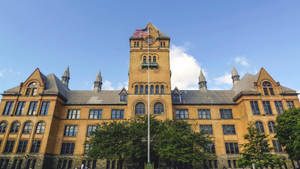 歷史悠久的大學建築，設有鐘樓和飄揚的美國國旗。 — 建築 壁紙