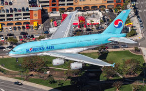 大韓航空空中巴士A380在城市上空低飛，下方有停車場和建築物。 — 城市景觀 壁紙