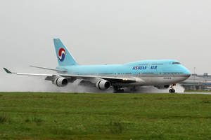 大韓航空波音747在潮濕跑道上降落，附近有草地。