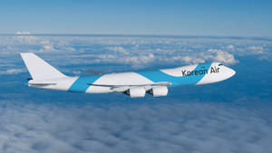 大韓航空貨機在雲層上方飛行，背景有山。