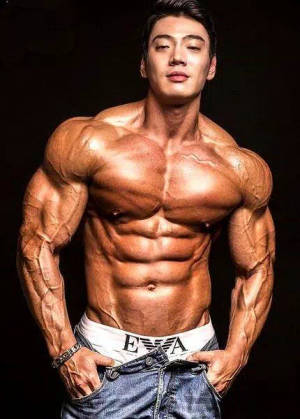 一位穿著牛仔褲和內褲的肌肉男在深色背景的攝影棚中擺姿勢。 — 健身房 壁紙