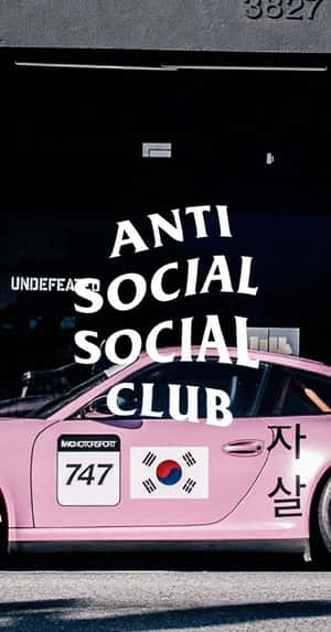 粉紅色賽車，帶有 anti social social club 品牌標誌和韓國國旗貼紙，停在車庫中。