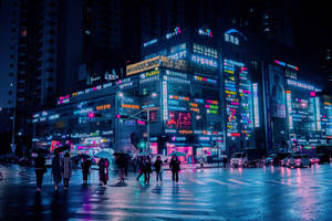 行人撐傘在夜晚穿越濕漉漉的霓虹城市街道。