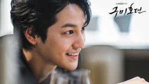 一個微笑的男士在燈光昏暗的餐廳裡手持酒杯。 — 成振宇 壁紙