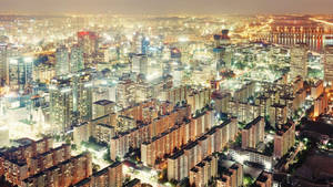 夜間俯瞰密集的城市景觀，建築物和街道閃爍著光芒。 — 夜景城市 壁紙