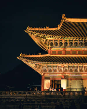 韓國宮殿的夜景，金色燈光與石牆上的遊客。 — 韓國 壁紙
