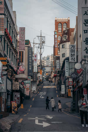 人們走在韓國一條狹窄的街道上，兩旁是色彩繽紛的招牌和建築物。 — Lenovo Legion Y900 13 壁紙