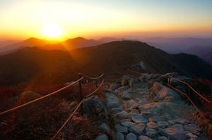 夕陽下的山徑，有繩索欄杆和遠方山峰