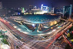 夜間城市景觀，帶有發光的圓頂建築和汽車燈光軌跡。 — MacBook Air 15 壁紙