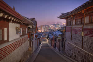 黃昏時分積雪的傳統韓國小巷，背景是現代城市燈光。