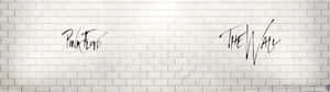 Pink Floyd The Wall 以黑色草書寫在白色磚牆上。