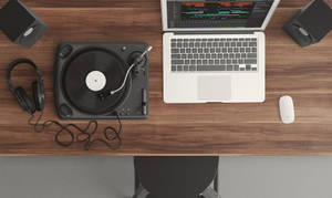 DJ 設置，木製書桌上有唱盤、手提電腦和耳機