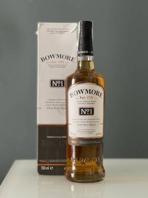 Bowmore No1威士忌瓶和盒子在白色表面上，背景灰色牆壁