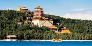 藍色湖泊上方山丘上的古老中國宮殿建築群，湖上有船。 — 建築 壁紙