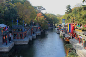 傳統中式運河，沿水邊有秋葉和彩色旗幟。 — 湖 壁紙
