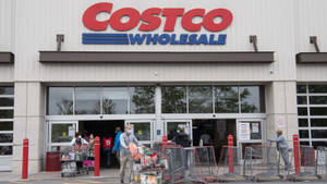 戴著口罩的購物者推著滿載的購物車離開 Costco。