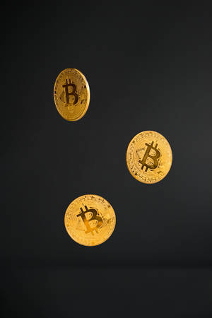 三枚漂浮的金色比特幣，背景為黑色。