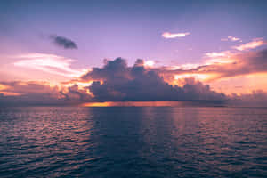 廣闊的海洋在日落時分，紫色和橙色雲彩倒映在平靜的水面上。 — 唯美雲朵動態 壁紙
