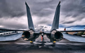 一架軍用戰鬥機在暴風雨天空下的濕滑停機坪上。