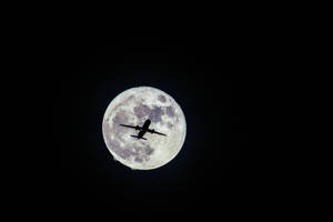 飛機在夜間飛過滿月前。