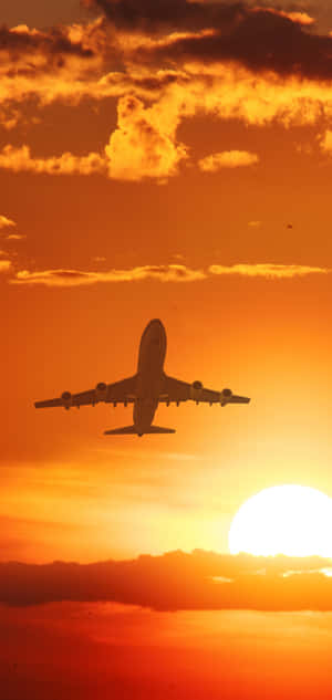 飛機在夕陽下飛行，天空呈現鮮豔的橙色和雲朵。 — Galaxy M17 壁紙