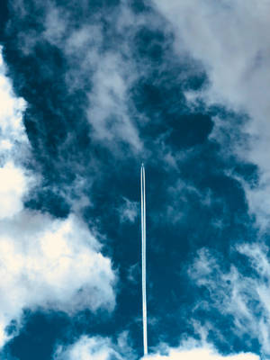 飛機在高空飛行，拖著長長的白線，背景是藍天白雲。