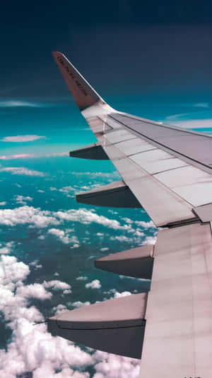 飛機機翼在明亮的藍天中翱翔於蓬鬆的白雲之上。 — 美學 壁紙