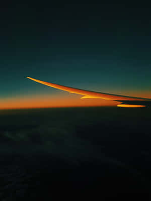 飛機機翼在雲層上方的橙色日落天空中呈現剪影。 — 森林 壁紙
