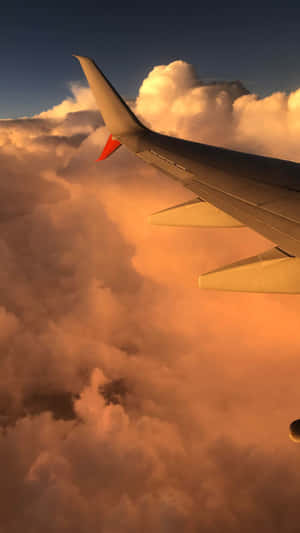 日落時分，飛機機翼翱翔於金色雲層之上。