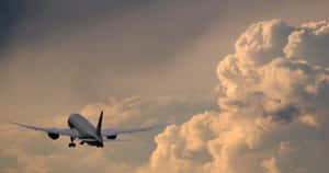 一架飛機在戲劇性雲彩的日落天空背景下接近著陸。 — 飛機 壁紙