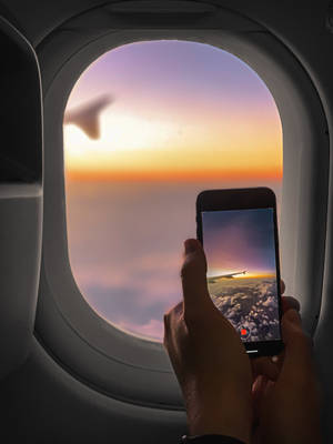手拿手機從飛機窗戶錄製日落 — 天空景觀 壁紙