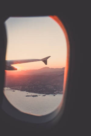 從飛機窗內看到的日落時分山脈與海洋上的飛機機翼。 — 旅行 壁紙